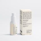 A small cylindrical cosmetic bottle with a white pump stands beside its tall rectangular box on a clean light gray studio background. Both the bottle and box are a warm off-white/cream color with black printed text and small icons.