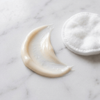 GentleRenew™ Eye Cream for Dark Circles jar with smooth cream texture next to green leaves on white background