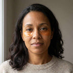 Caffeine Eye Patches are translucent amber hydrogel under-eye patches worn by a woman, with a smooth curved shape