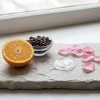 Caffeine Eye Patches are clear, curved hydrogel patches shown with orange, coffee beans and pink rose petals