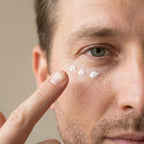 Eye Cream for Men shown as white cream dots beneath a man's eye, gently patted onto the skin with a fingertip