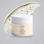 Face and Body Scrub in a pale cream jar with a white lid, shown with creamy scrub and visible black volcanic sand