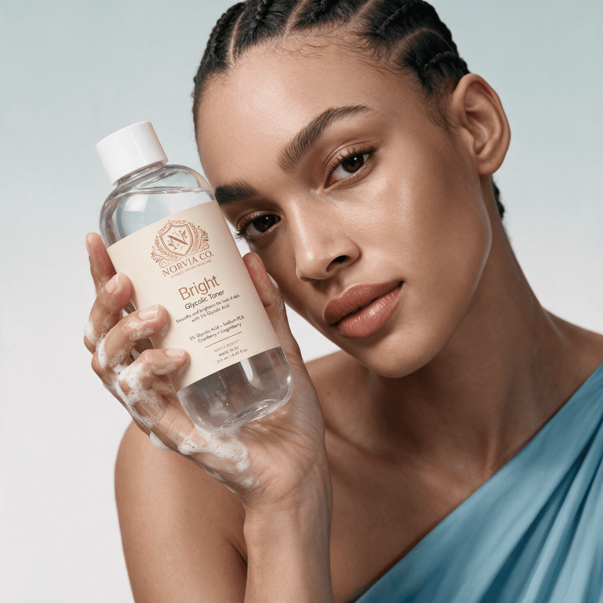 Glycolic Acid Toner in a clear bottle with a white cap and cream label, held beside a woman's face