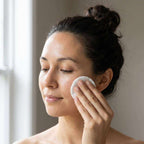 Glycolic Acid Toner applied with a white cotton pad across a woman's cheek during a skincare routine