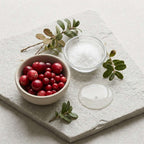 Glycolic Acid Toner ingredients shown with red cranberries, green berry leaves, clear powder and translucent liquid