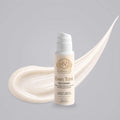 Kojic Acid Scrub in a white Norvia pump bottle with gold lettering, beside a creamy off-white exfoliator swatch