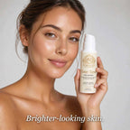 Kojic Acid Scrub in a white pump bottle with gold and brown label, held beside a woman's face