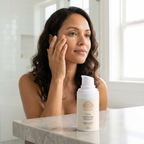 Peptide Eye Cream in a white pump bottle beside a woman gently applying the cream under her eye