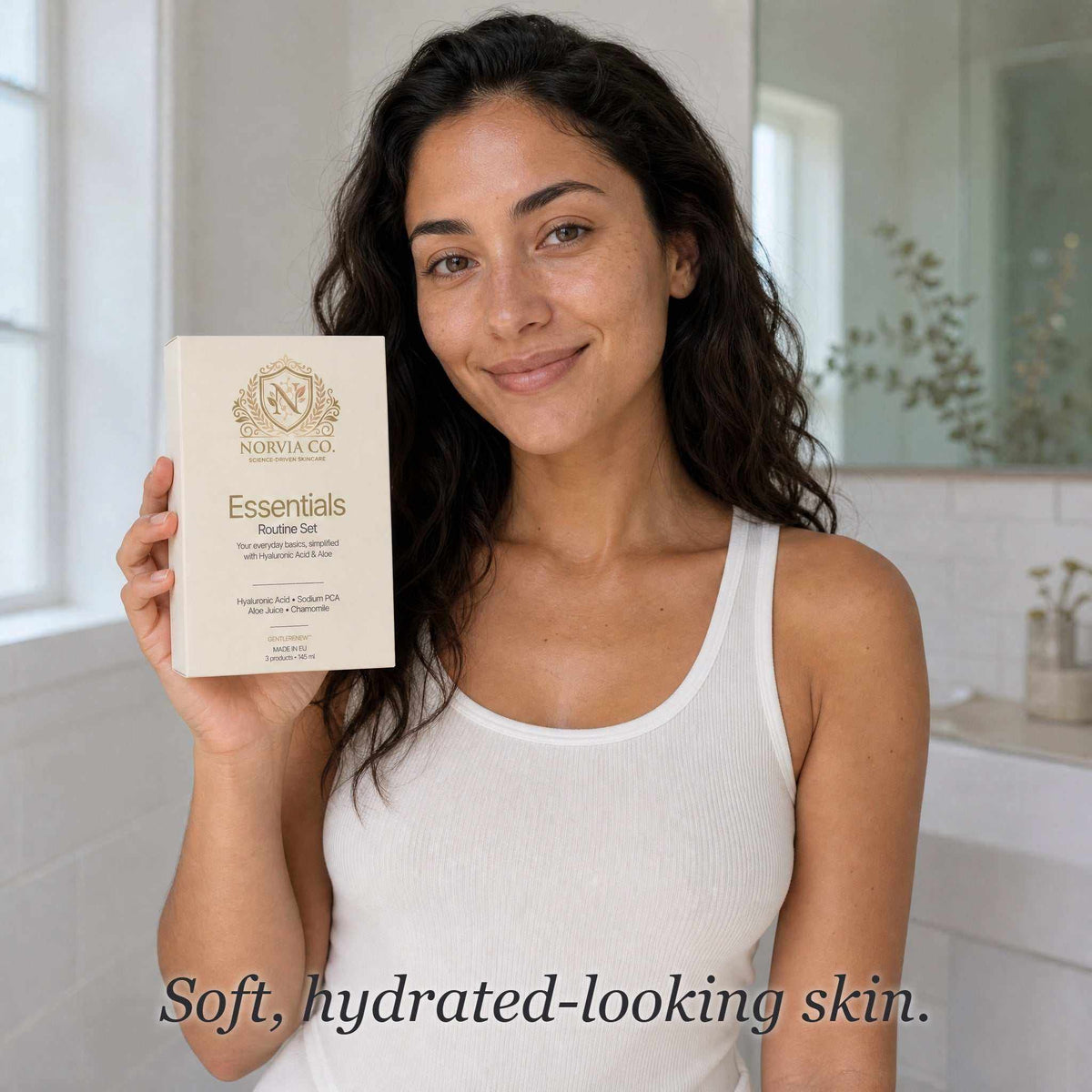 Skin Care Routine Kit in a cream Essentials Routine Set box with gold lettering, held by a woman