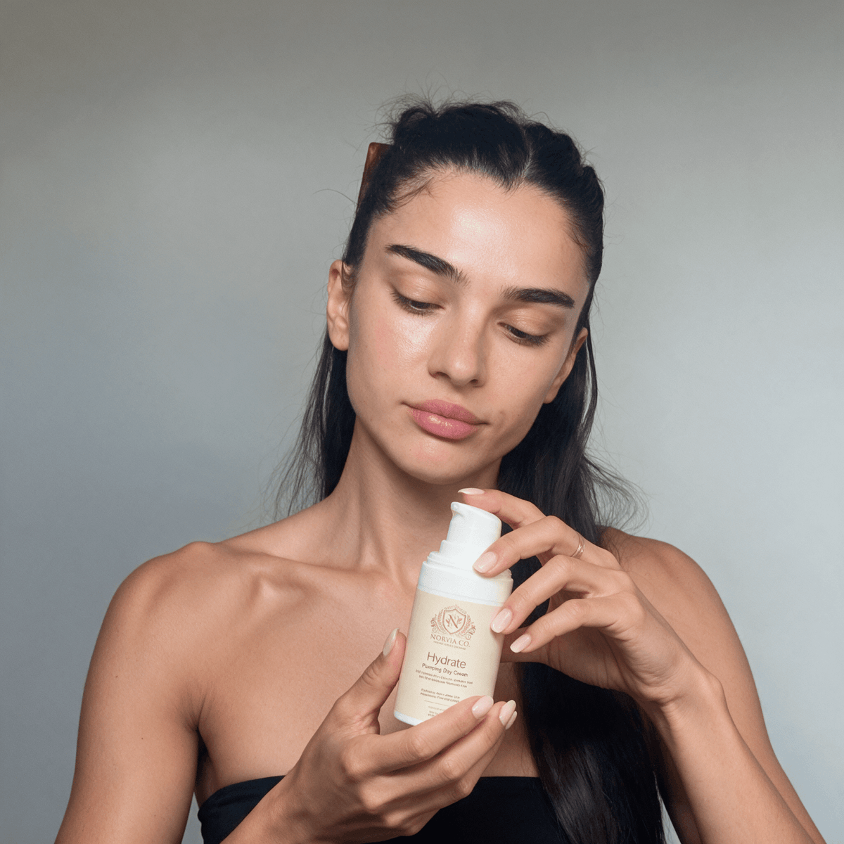 Skin Care Routine Kit featuring a woman holding a white Hydrate skincare pump bottle with a beige label