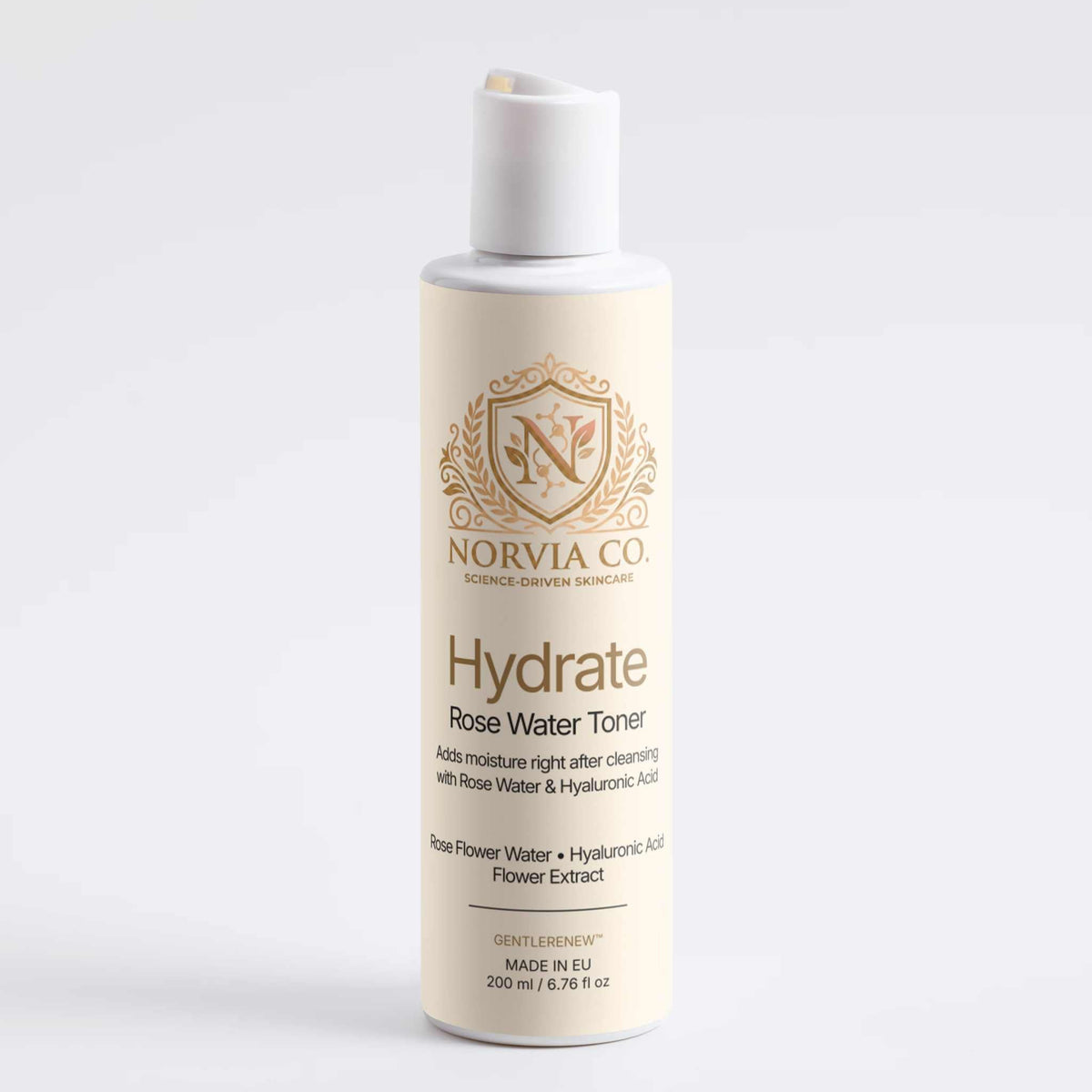 A bottle of Norvia Co. Hydrate Rose Water Toner with a white cap and cream-colored body, featuring gold lettering and a crest logo, set against a plain light gray background.