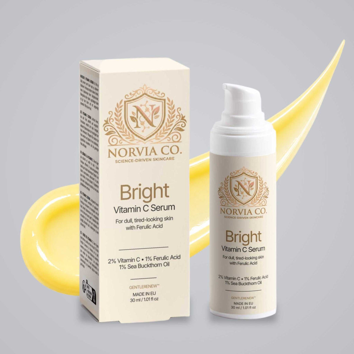 Vitamin C Serum in a white bottle with gold branding beside a matching cream box, featuring a gold botanical emblem